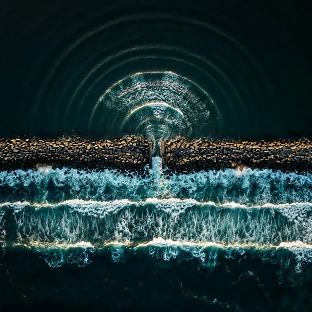 Ocean waves diffracting through a gap in a breakwater, spreading in circular arcs